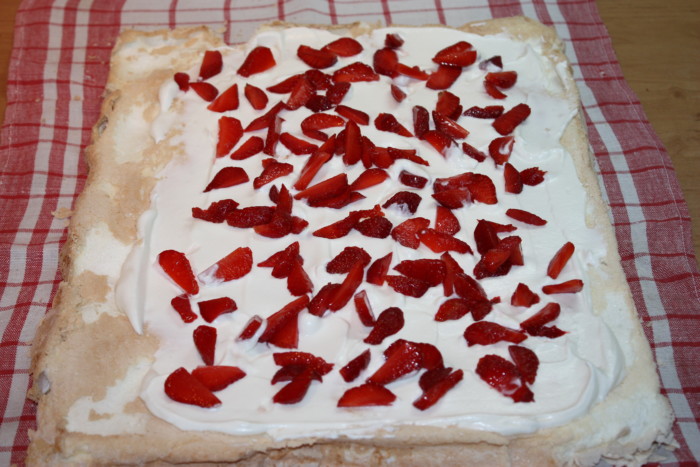 Meringue roll with whipped cream and strawberries